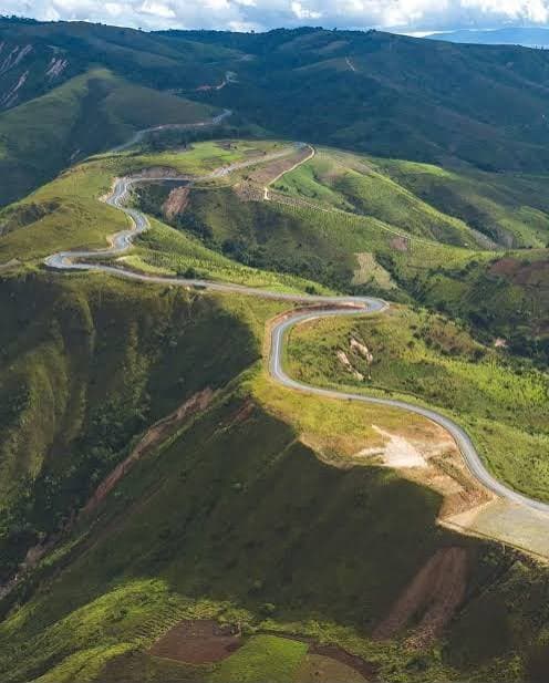 Aerial view of a road winding through green hills